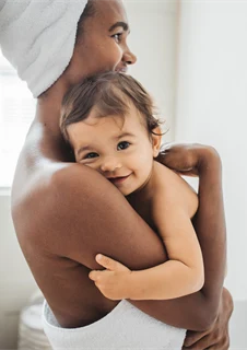 Mamma som håller ett glatt nybadat barn.