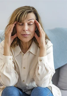 Kvinna med huvudvärk som masserar sina tinningar.