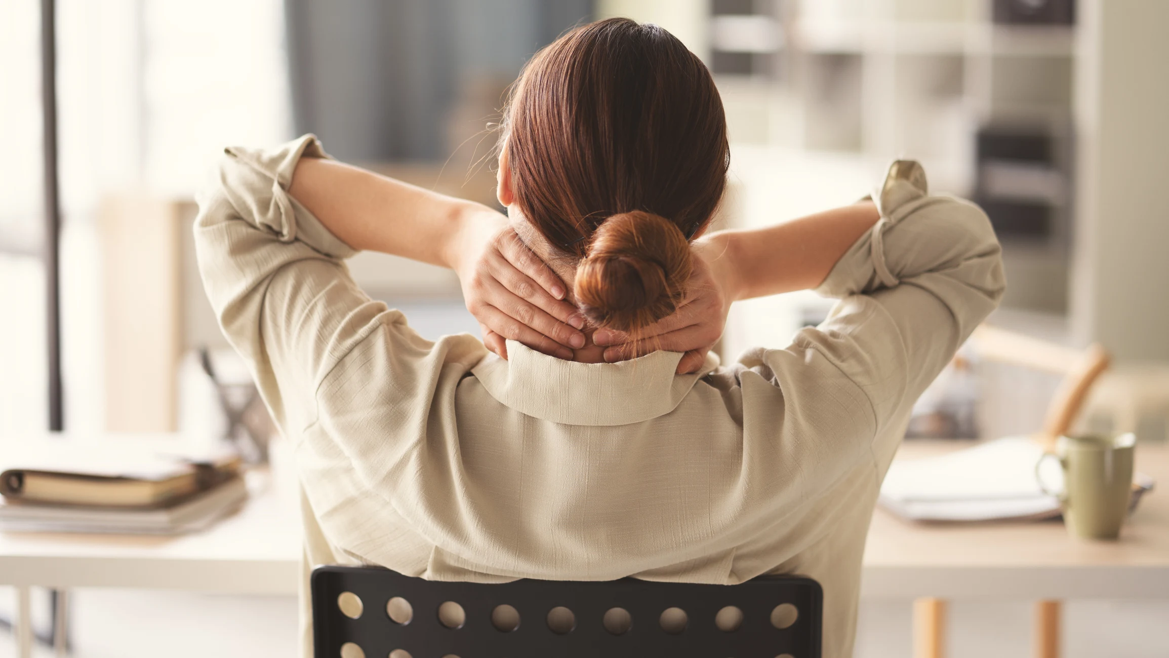 Kvinna med smärta och värk som masserar sin nacke.