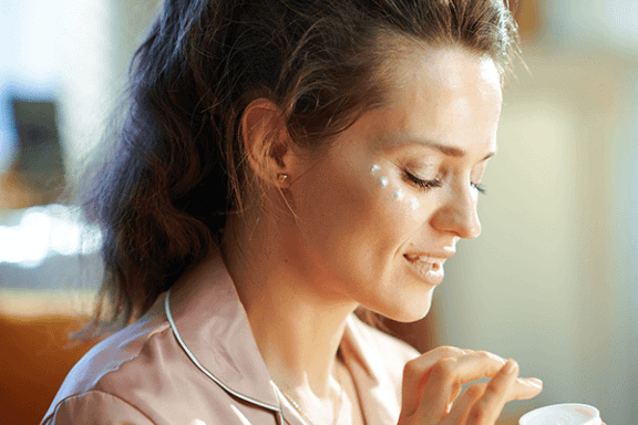 Tjej som applicerar ögonkräm för rynkor under ögonen.