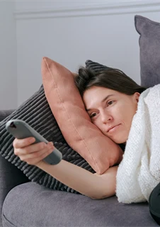 Kvinna med covid som ligger och tittar på tv.