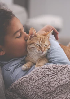 Tjej som gosar med en katt. Något personer med kattallergi tyvärr måste avstå.