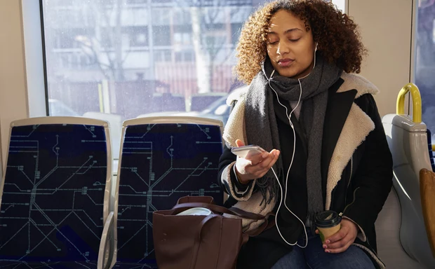 En kvinna sitter på tunnelbanan och tittar ner på sin mobil.