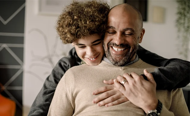 En glad pojke kramar om sin pappa.