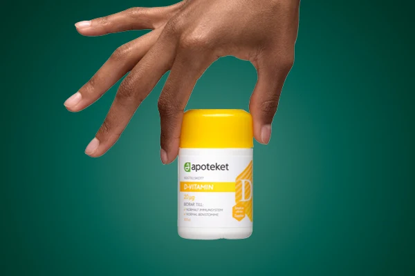 En hand visar upp kosttillskottet "D-VITAMIN" från apoteket.