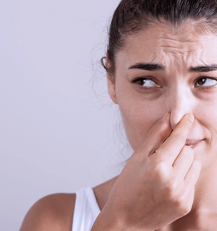 En kvinna som håller för sin näsa. 