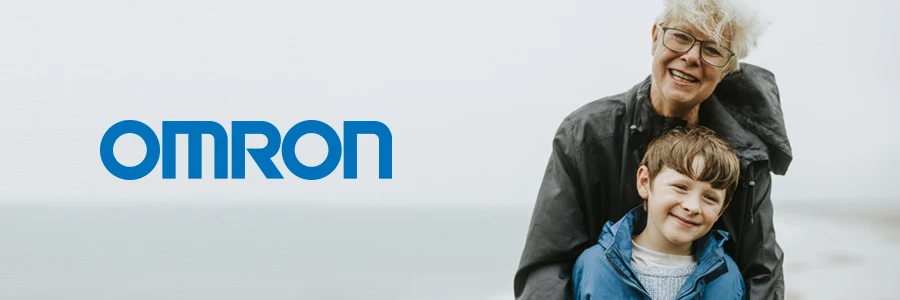 En äldre dam håller om en ung pojke vid havet. Text på bild lyder: Omron.