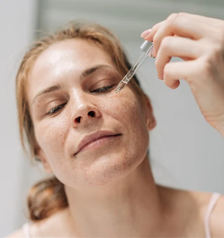 Kvinna som applicerar serum med ectoin.