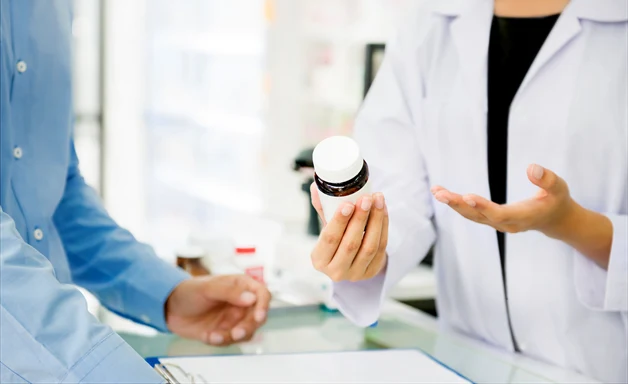 En farmaceut som pratar om en medicin med en kund.