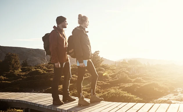 Två personer som går på en vandringsled, solen skiner.