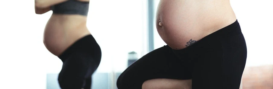 En gravid kvinna som utövar yoga i stående position.
