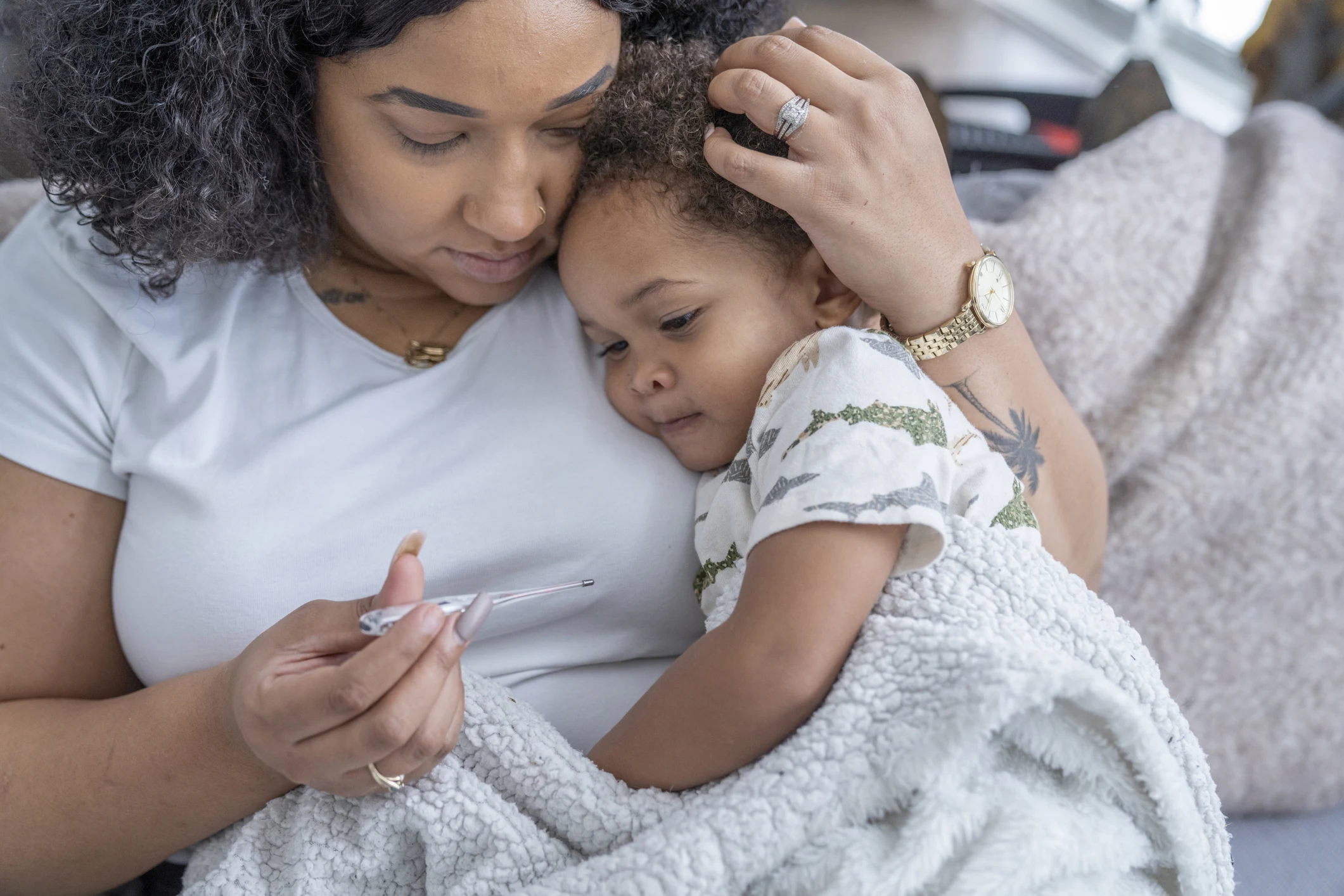Mamma som tar tempen på sitt lilla barn med RS-virus.