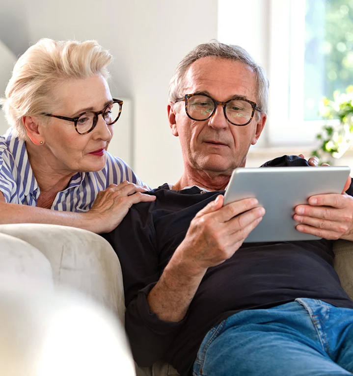 En äldre man och kvinna tittar på en ipad.