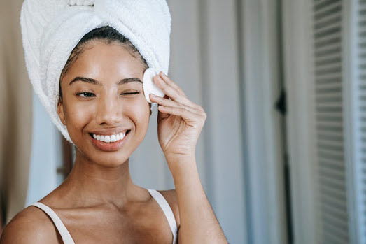 Kvinna med känslig hud som applicerar toner med en bomullsrondell.