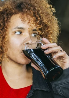 Kvinna dricker coca cola som innehåller socker som kan leda till hål i tänderna.