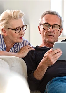 En äldre man och kvinna tittar på en ipad.