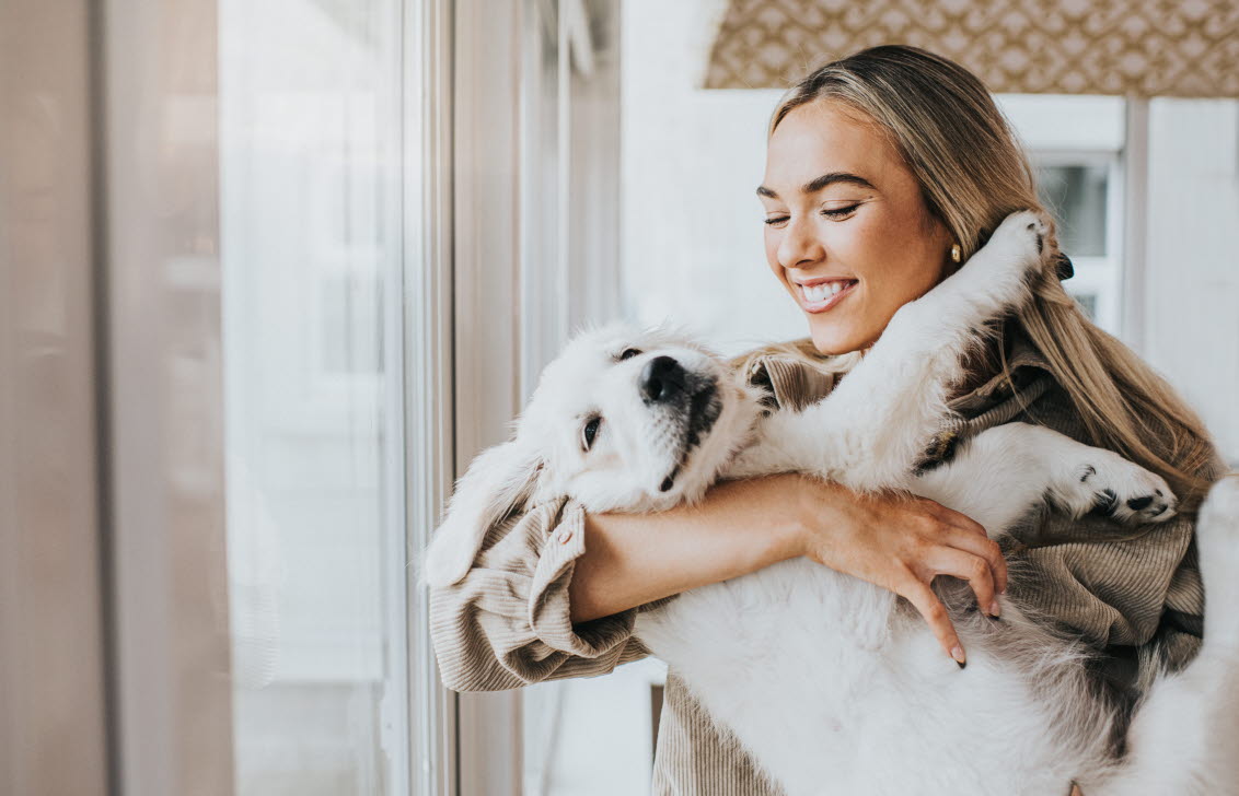 	En ung kvinna kramar en golden retriever‑valp.