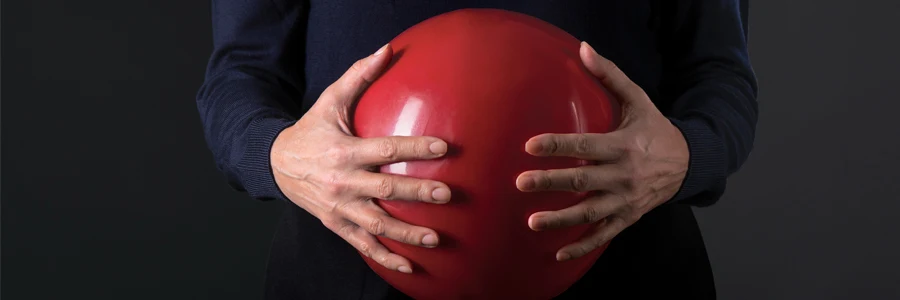 En person som håller en röd boll framför sin mage. 