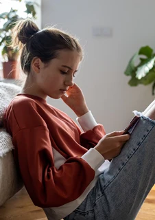 Ung, deprimerad tjej som tittar i sin mobiltelefon.