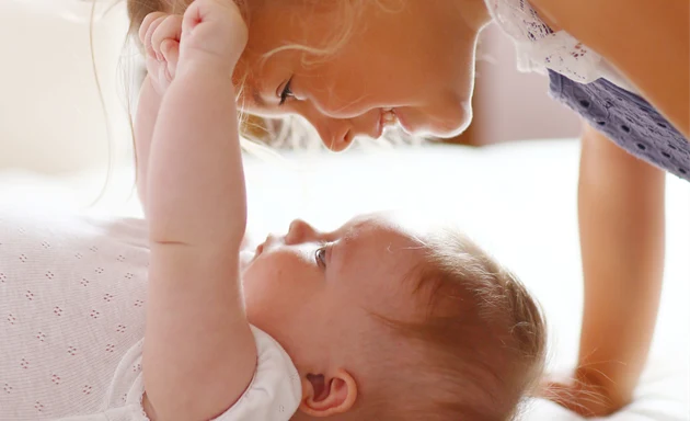 Baby och barn - flicka som leker med sitt lilla syskon.