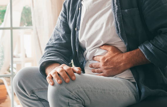 En man håller ena handen för magen.