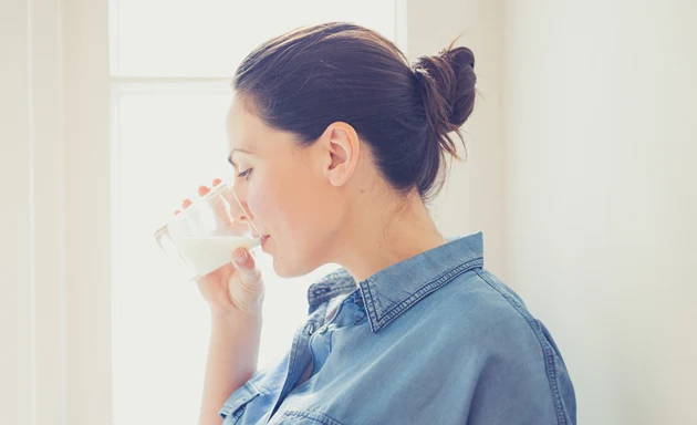 Laktosintolerant kvinna som dricker ett glas mjölk.