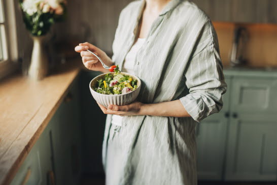 En kvinna som äter en sallad.