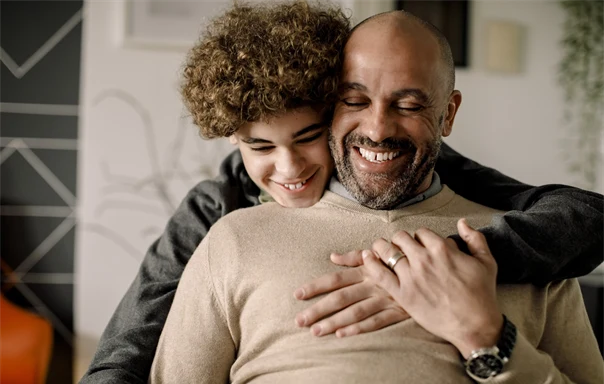 En glad pojke kramar om sin pappa.