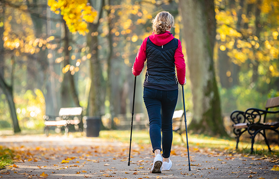 Kvinna som går powerwalk med stavar.