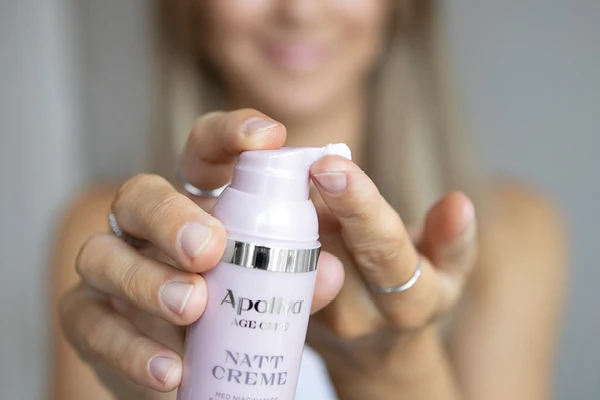 En kvinna pumpar ut produkt från en Apoliva nattkräm. 