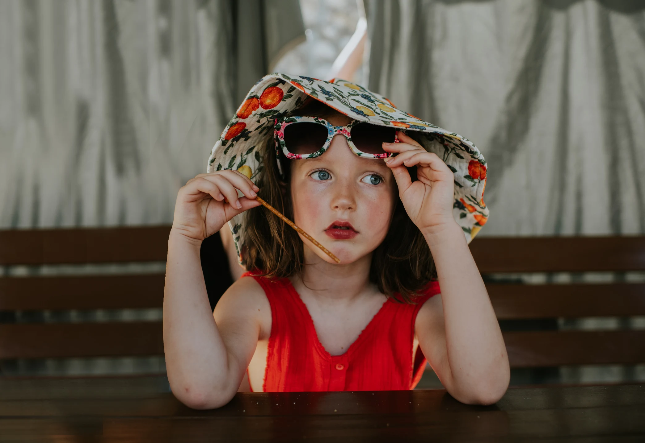 Flicka med solhatt som tar skydd i skuggan på en varm dag.