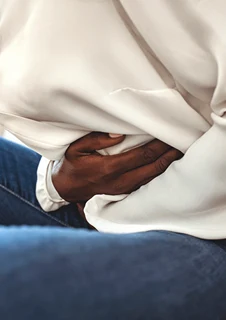 En person håller båda händerna om magen.