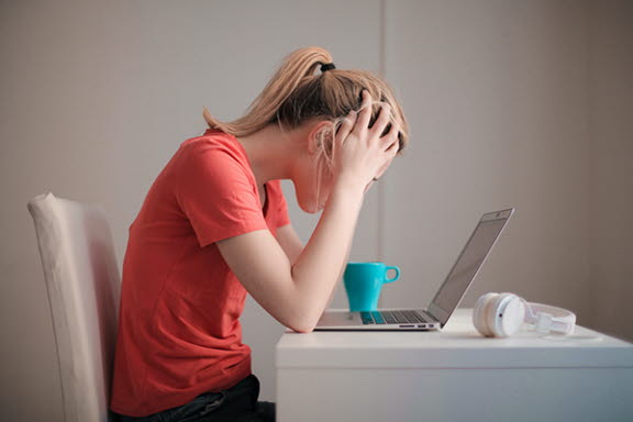 Stressad tjej som sitter vid sin dator.