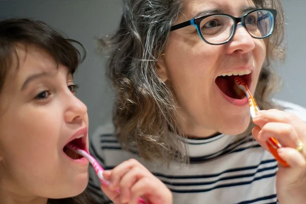 En mamma borstar tänderna tillsammans med sitt barn. 