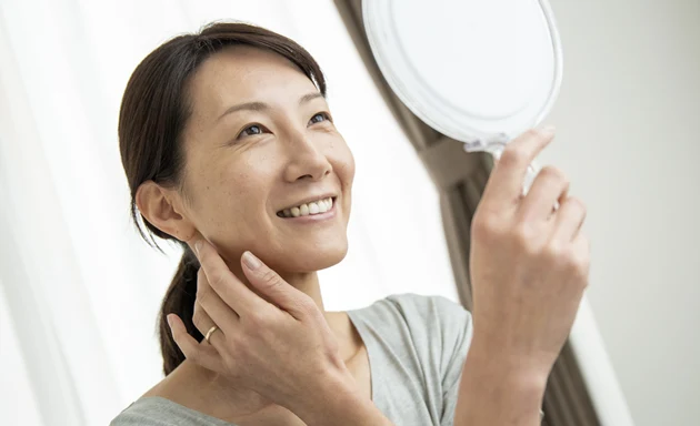 Kvinna med torr hy som ser sig i spegeln.