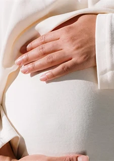 En gravid kvinna som håller händerna om magen. 