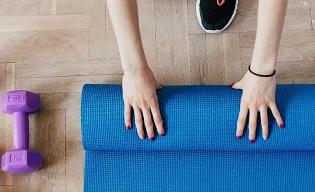 En person som rullar ihop en yoga-matta.