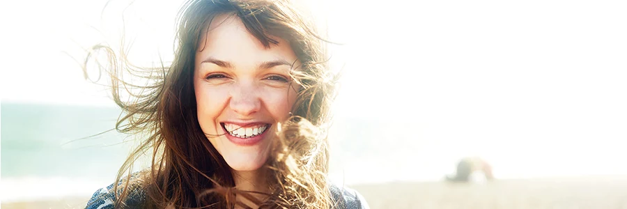 En kvinna som ler på en strand. 