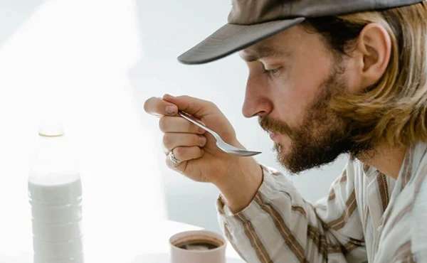 En man äter mat med en sked. 