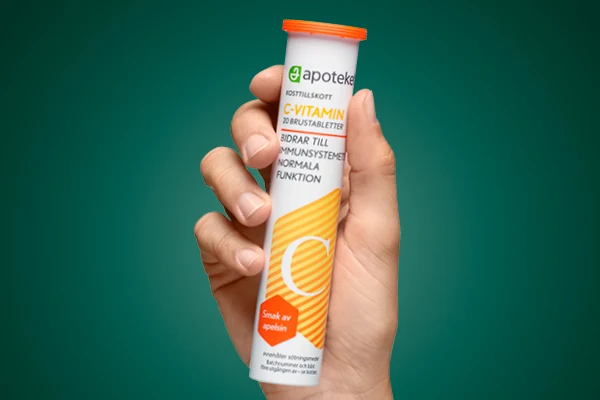 En hand visar upp kosttillskottet "C-VITAMIN" från apoteket.