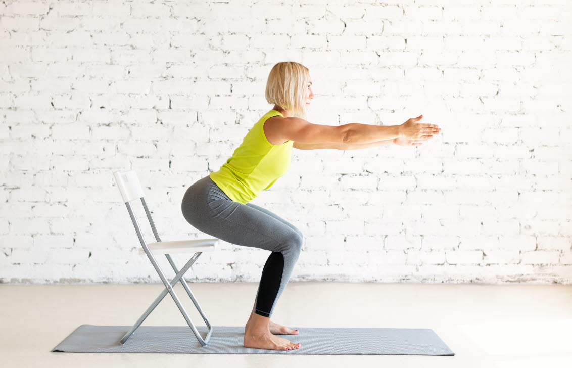En kvinna sätter sig på en stol, utan att ta stöd, för att träna balansen.
