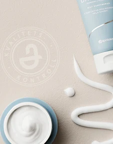 Hudvårdsprodukter arrangerade på ett bord, inklusive en blå flaska, tuber och en burk med kräm.