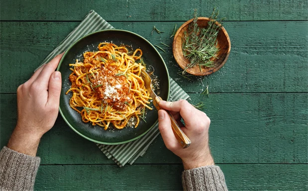 Spagetti på tallrik, serverad med sås och färska kryddor.