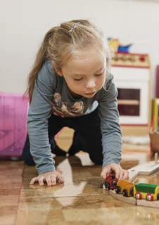 Två barn sitter på golvet i en förskola och leker med leksaker.