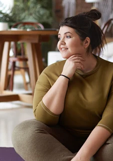 Leende tjej som sitter på en yogamatta.