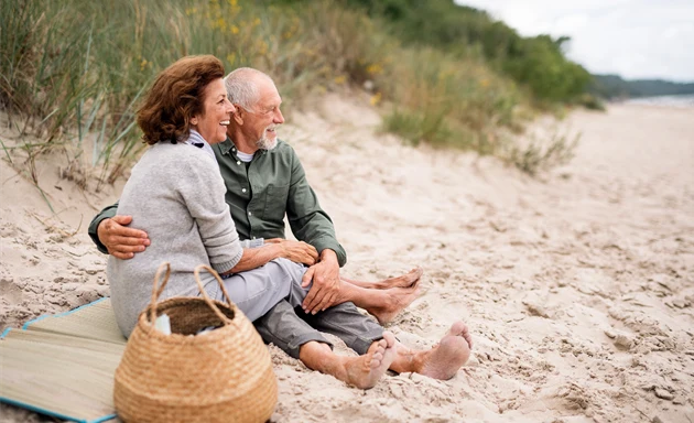 En äldre man och kvinna håller om varandra på stranden.