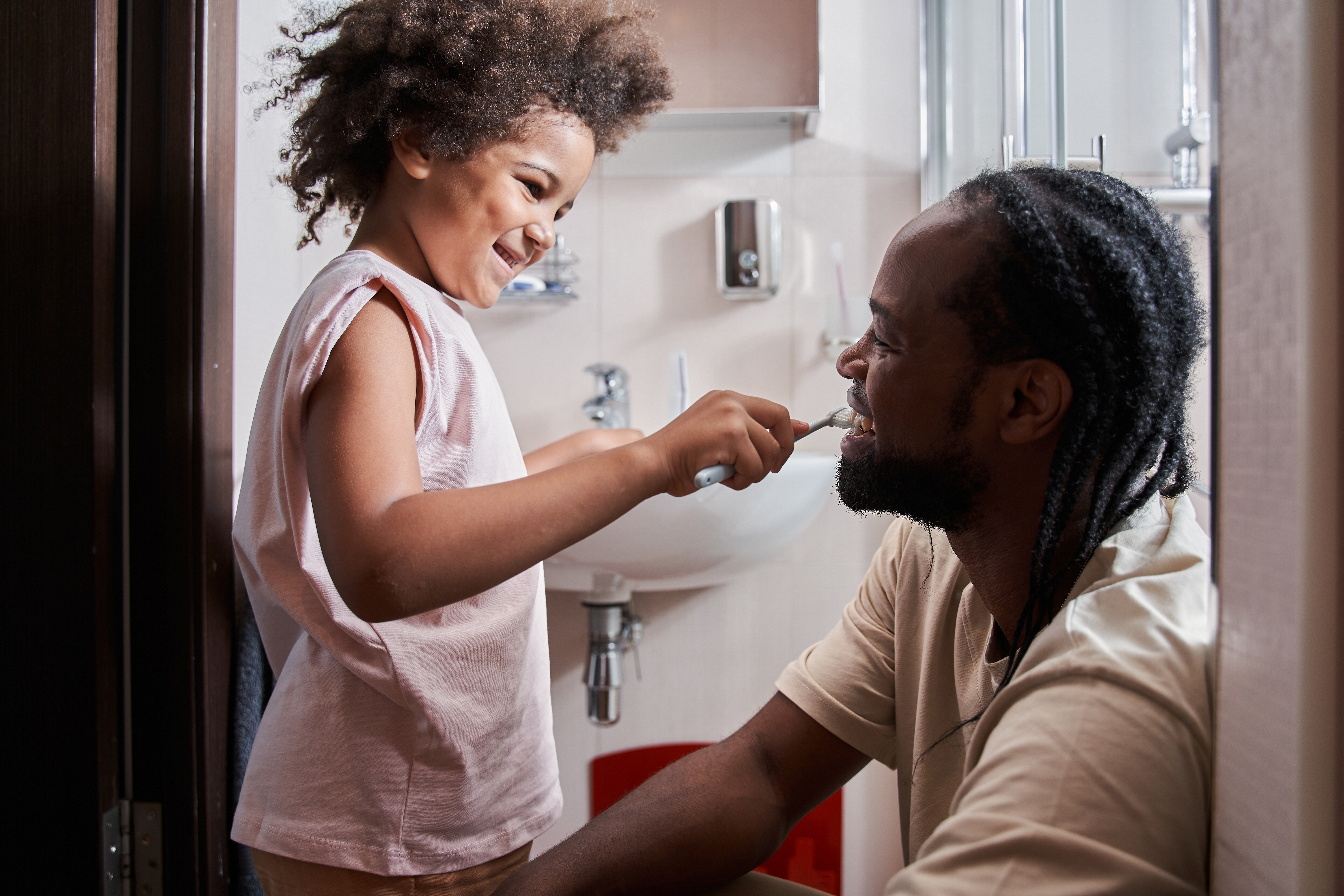 Barn borstar en vuxens tänder lekfullt.