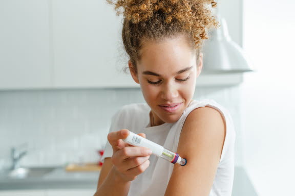 Tjej med nötallergi som tar en adrenalinpenna.