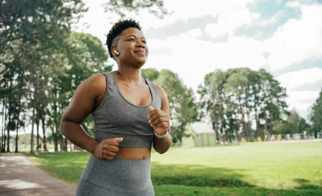 En kvinna joggar ute på landsbygden en sommardag.
