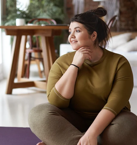 Leende tjej som sitter på en yogamatta.